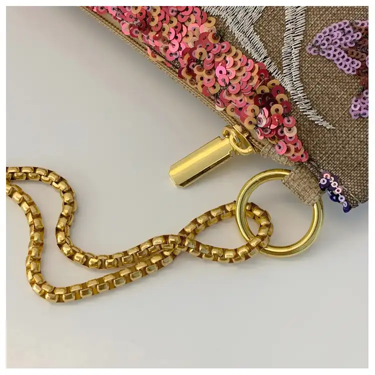 Beach party setting featuring small linen clutch bag with sparkling sequined embroidery details.
