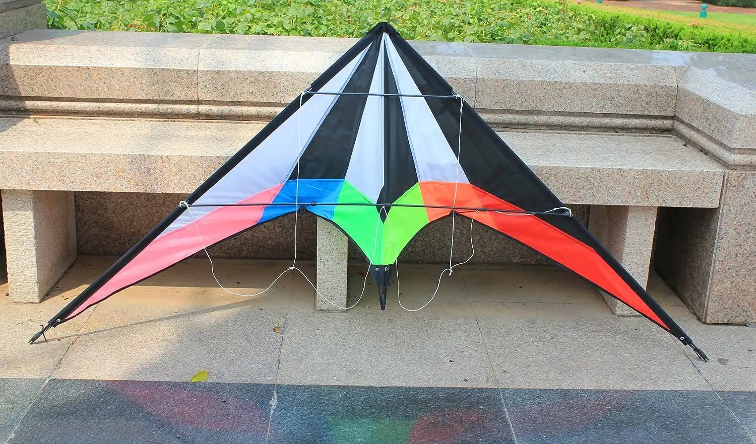 Advanced pilot controlling rainbow stunt kite with dual lines demonstrating precision flying.