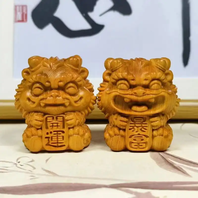 Natural cypress wood foo dog statue held in hand demonstrating actual size and portable design.