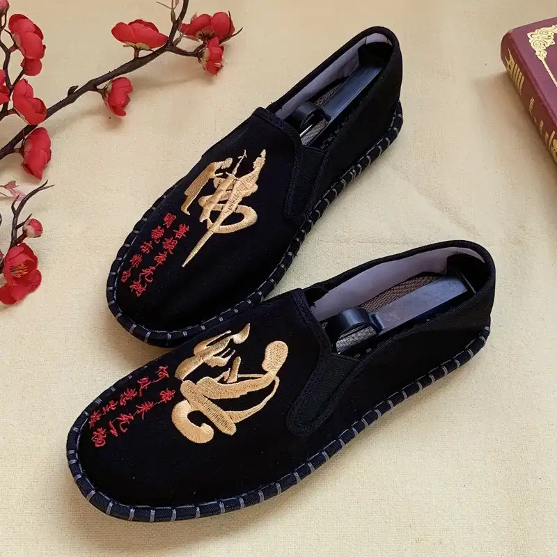 Pair of Chinese vintage shoes arranged on traditional fabric background showcasing totem patterns.