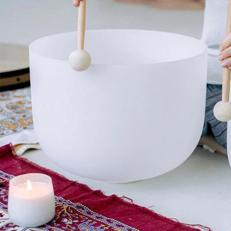Sound healing therapist demonstrating proper crystal bowl playing technique with mallet.