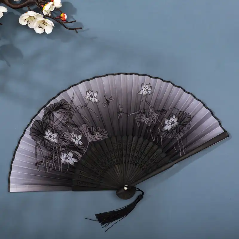 Outdoor summer event with people using folding fans for cooling and style.