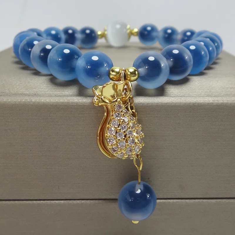 Fashionable women's crystal bracelet with blue agate beads and symbolic pendant charm.