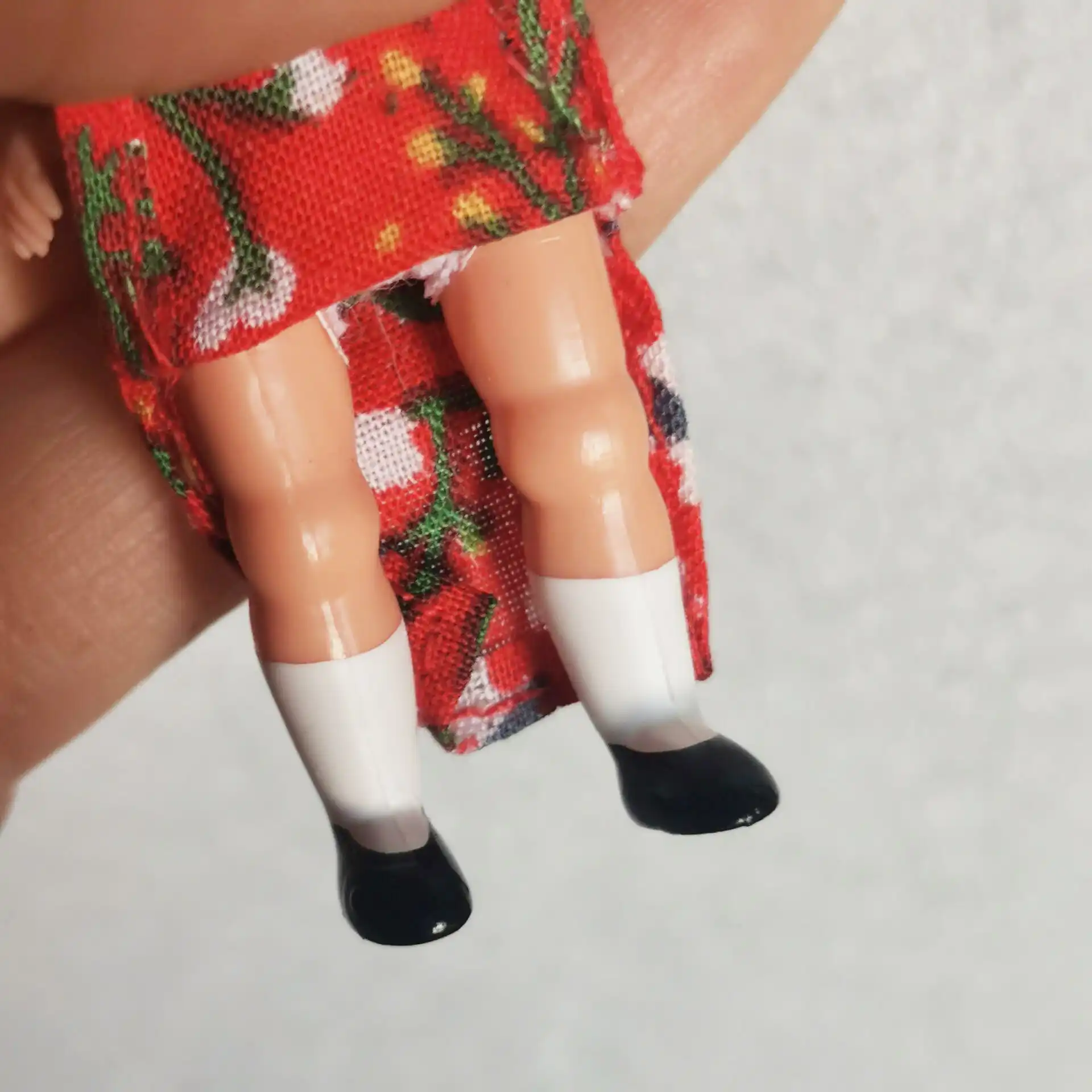 Detail shot of vintage cheongsam dress patterns and decorative elements on miniature doll.