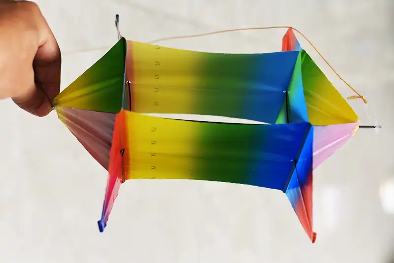 Colorful PE rotating fish kite flying in blue sky with cartoon design clearly visible.
