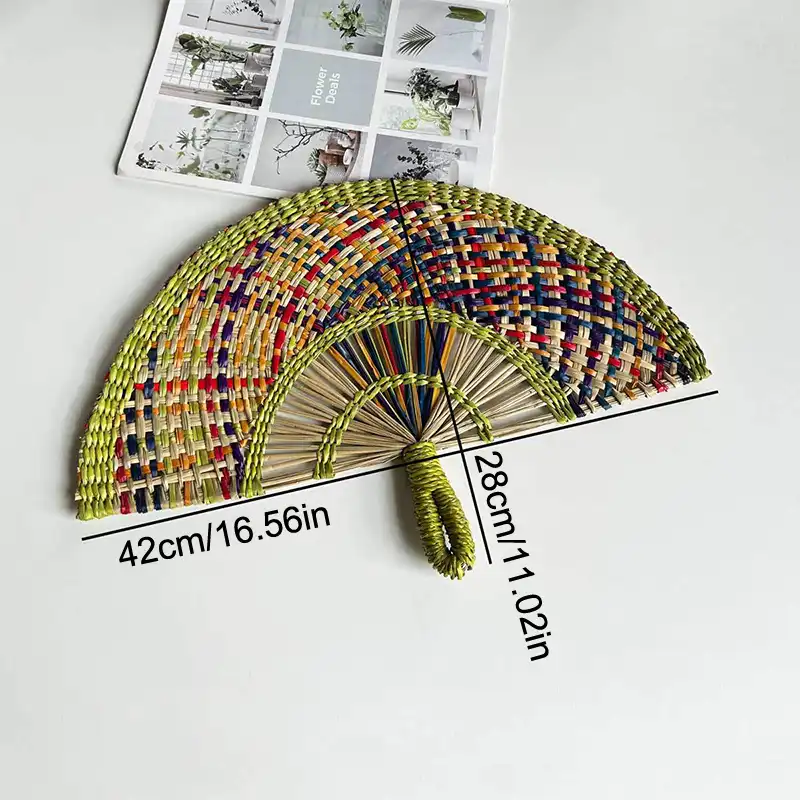 Natural straw fan photographed against neutral background showing 42x28cm size proportions.