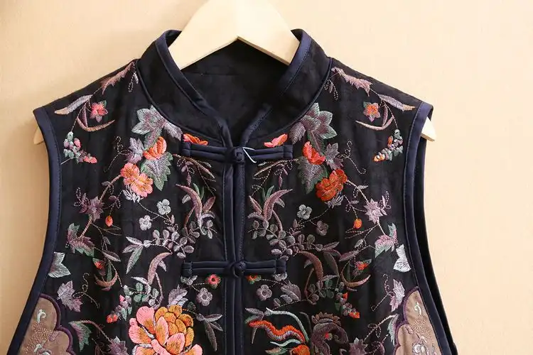 Close-up detail of delicate flower embroidery on cotton linen fabric vest front panel.