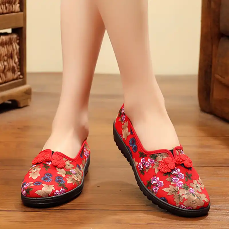 Traditional Chinese embroidered shoes arranged on fabric background showcasing ethnic cultural heritage.