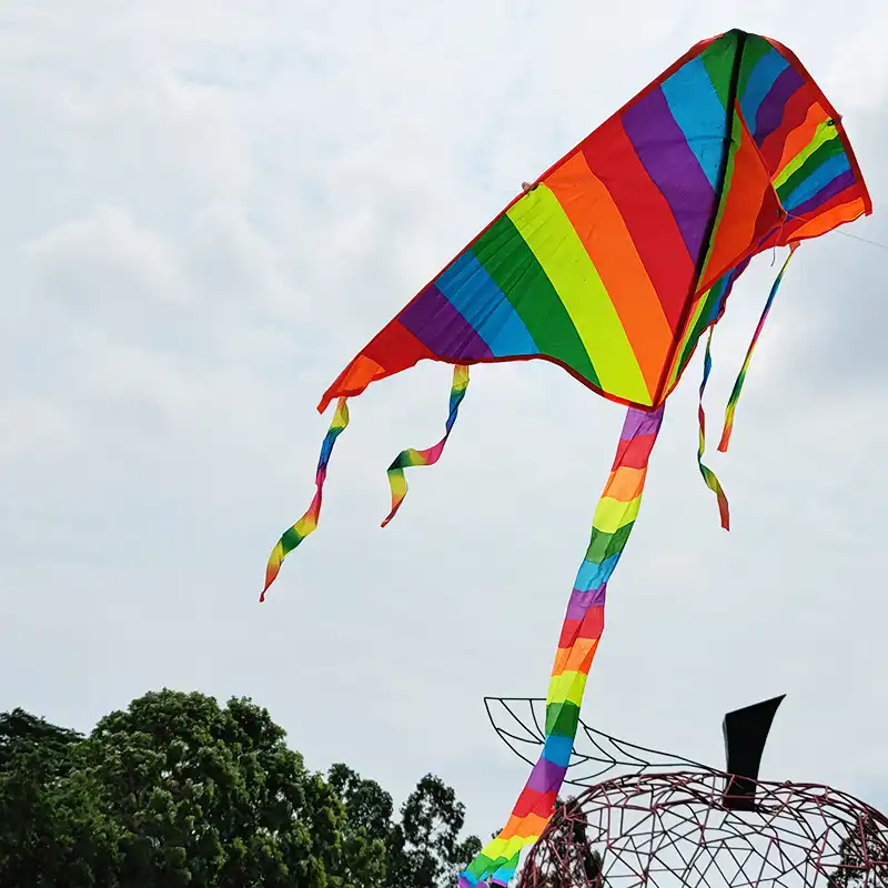 Close up view of rainbow triangle kite showing vibrant color stripes and nylon material quality.