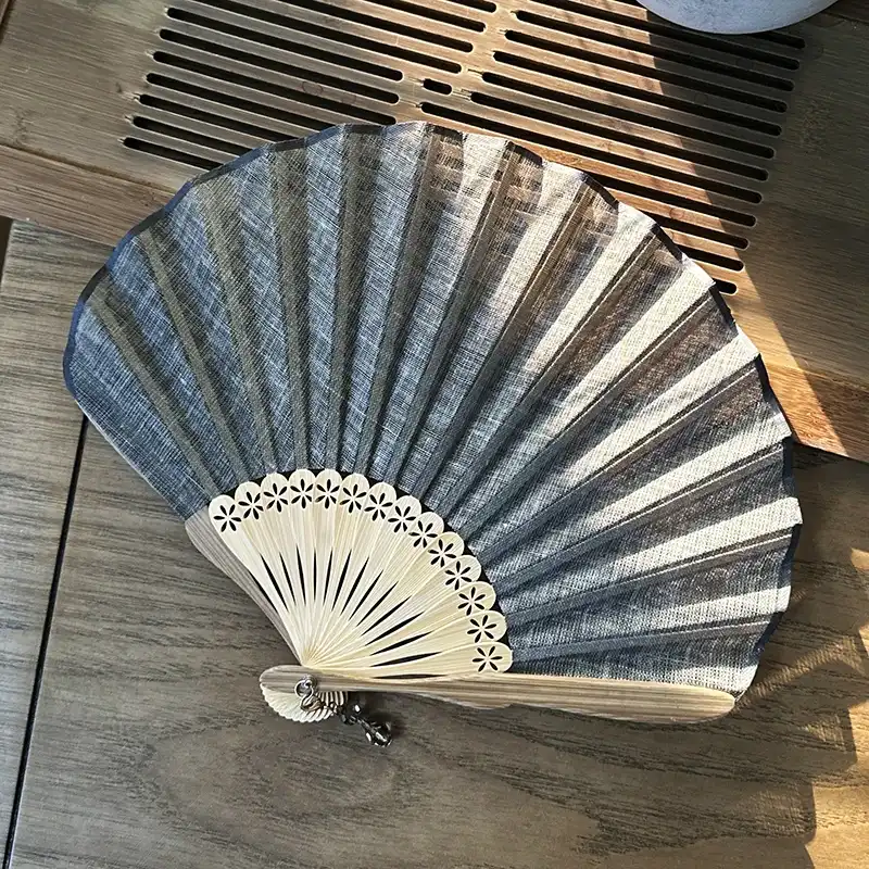 Model holding open shell shaped fan showing proper grip and elegant hand positioning technique.