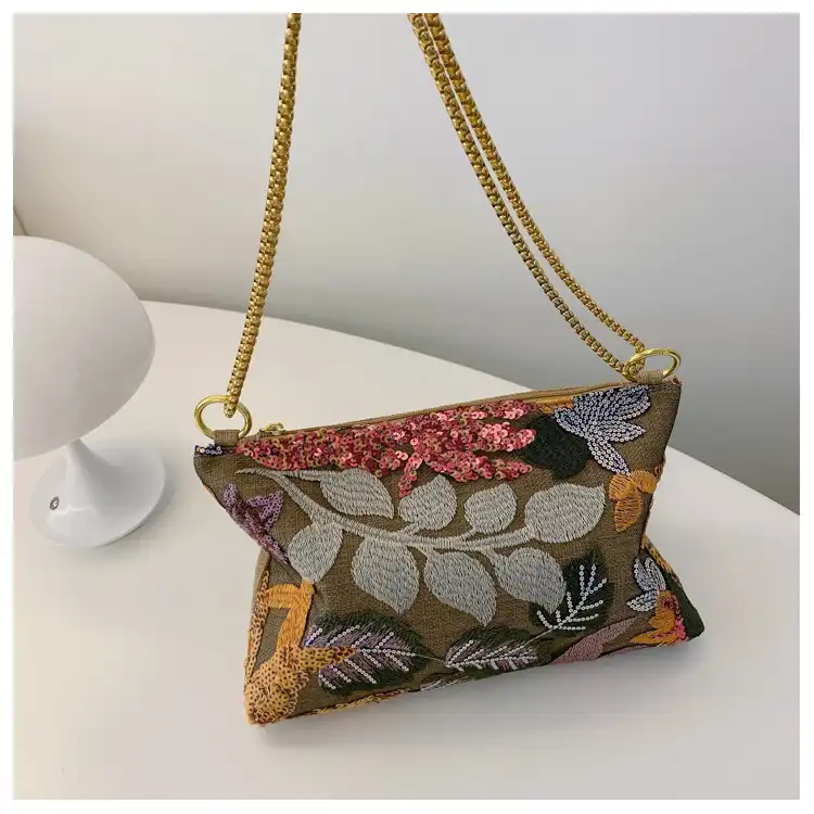 Zipper closure detail of embroidered clutch ensuring secure storage for personal belongings.