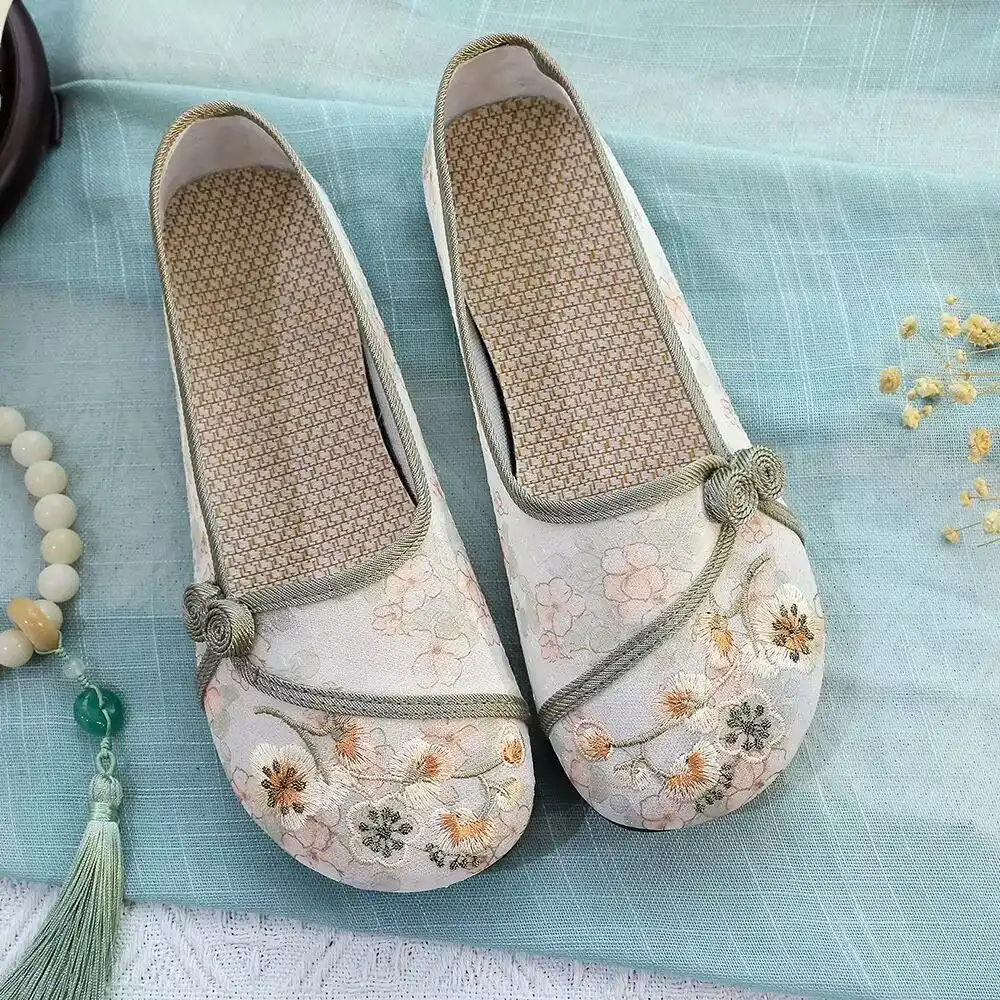 Womens feet wearing Old Beijing cloth shoes in natural outdoor garden setting.