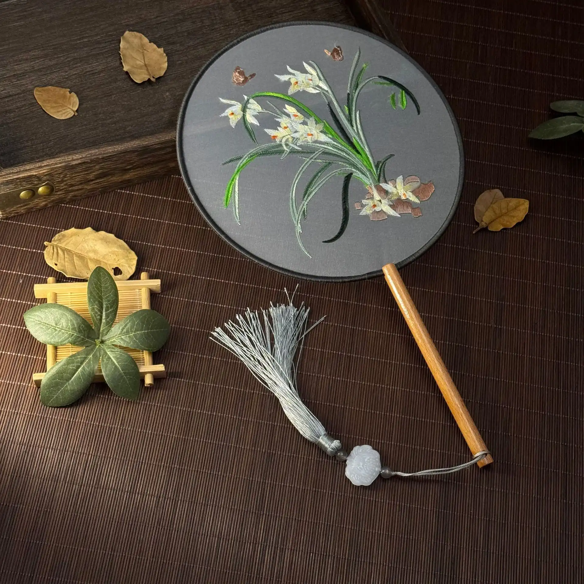 Qipao costume styling with embroidered round fan as authentic traditional accessory.