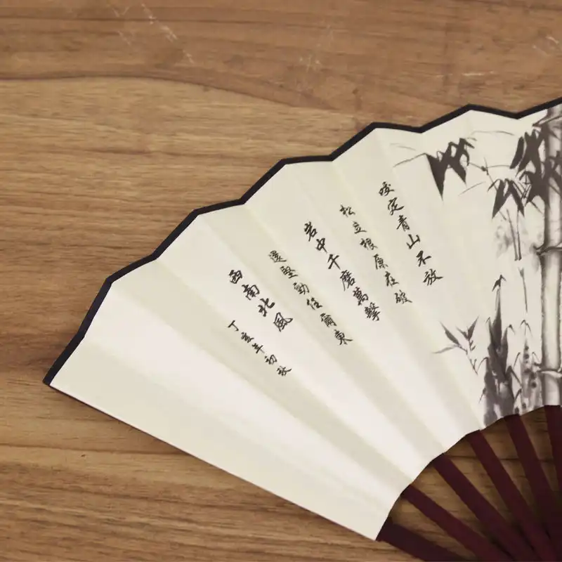Person using silk fan for cooling demonstrating practical functionality during warm weather.