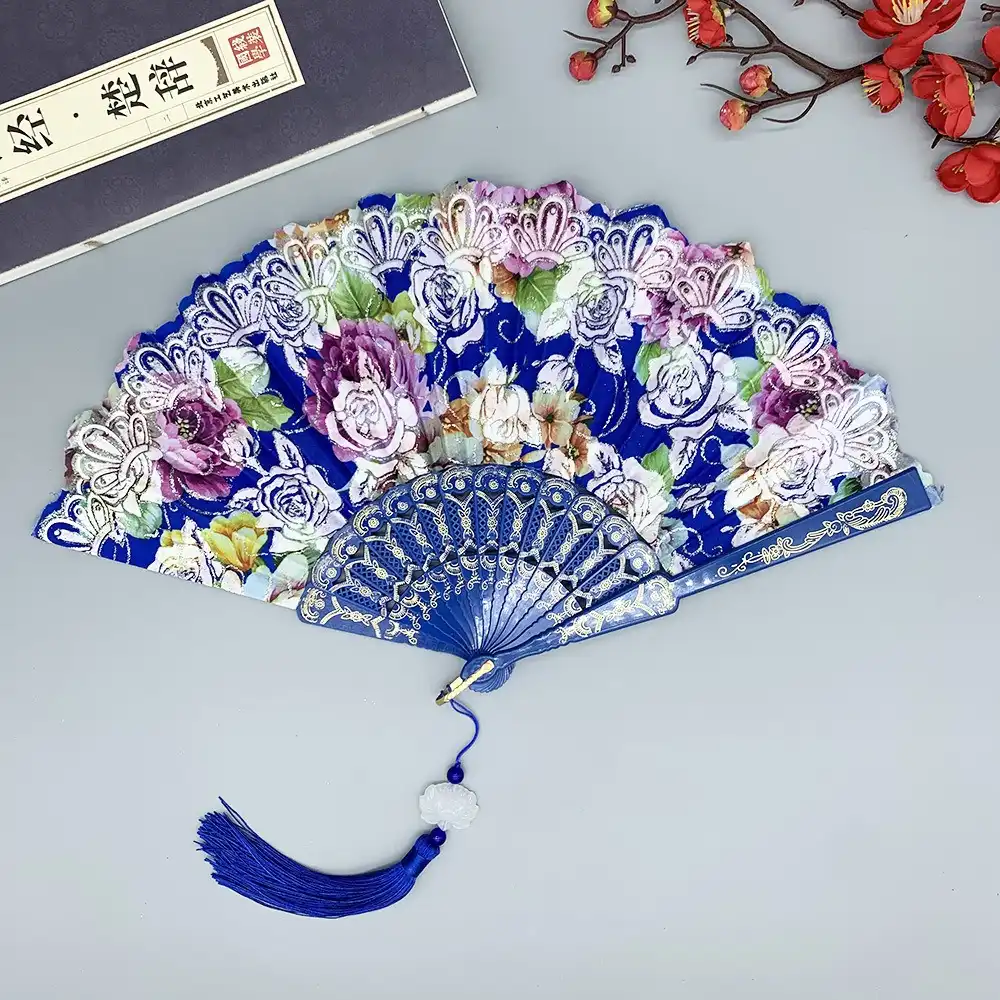 Stage performer using silk folding fan with tassel in theatrical dance performance.