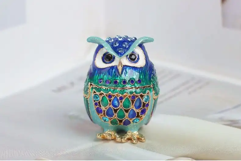 Elegant enamel owl jewelry box arranged with home decor accessories for display styling.